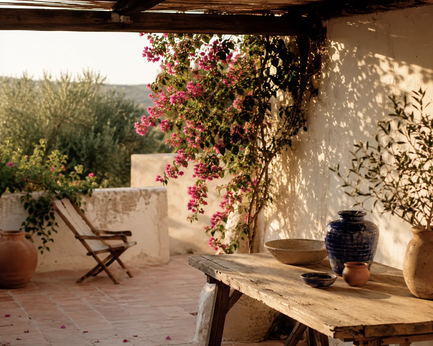 A quiet Mediterranean courtyard at golden hour with handmade ceramics on a wooden table.